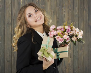 Güzel genç gülümseyen kadın hediye kutuları ve çiçeklerle. Genç iş kadını. Genç ve güzel öğretmen