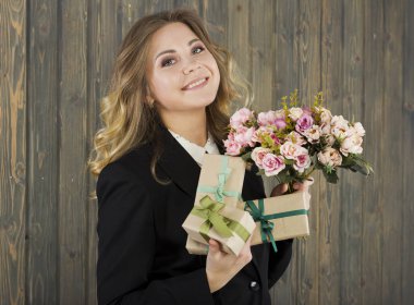 Güzel genç gülümseyen kadın hediye kutuları ve çiçeklerle. Genç iş kadını. Genç ve güzel öğretmen