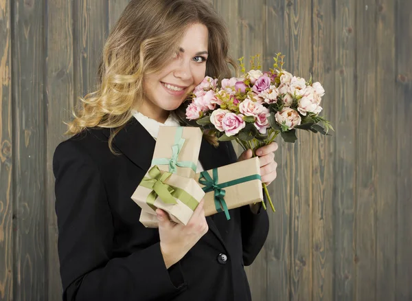 Güzel genç gülümseyen kadın hediye kutuları ve çiçeklerle. Genç iş kadını. Genç ve güzel öğretmen