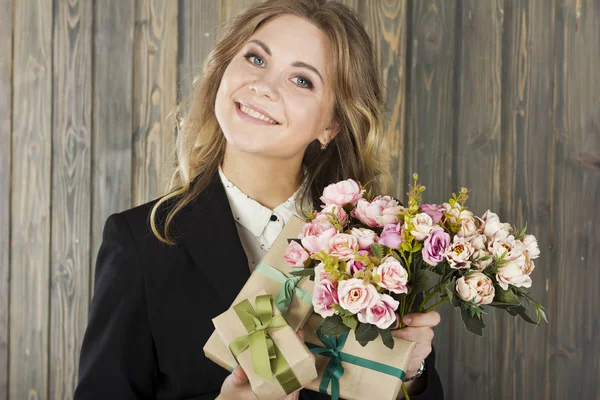 Beautiful young smiling woman with gift boxes and flowers.Young business woman. Young and beautiful teacher