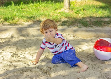 Çocuk kum havuzunda kumla oynuyor.