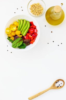 Beyaz masada taze sebze salatası. Dilimlenmiş domates, avokado ve biber yeşillikile. 