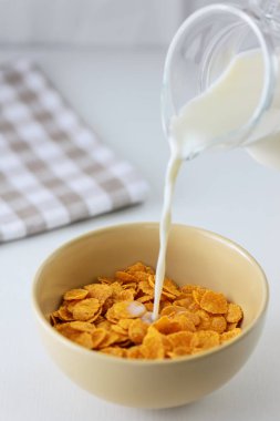 beyaz bir masada bir tabakta süt ile mısır gevreği