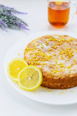 Beyaz ahşap bir masada bir fincan çay ile Limon pasta