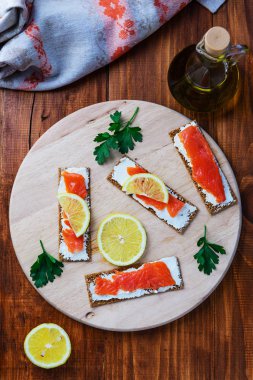 Ahşap yuvarlak tahta üzerinde somon, limon ve otlar ile Sandviçler