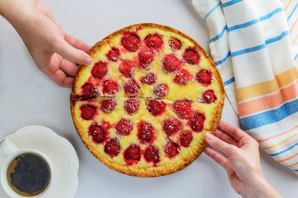 Homemade strawberry pie with coconut chips. The hand takes a slice of pie