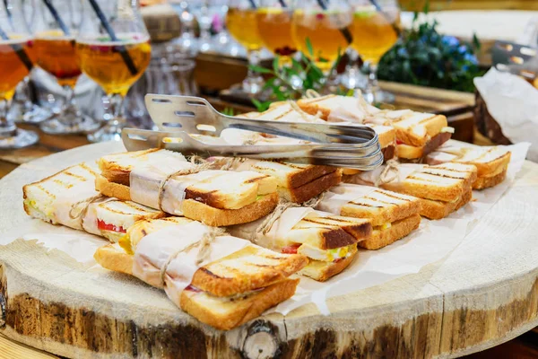 Sandwiches on a wooden board at an open air party.