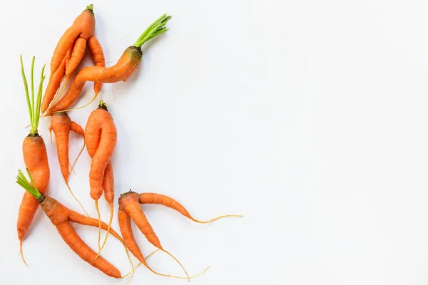 Ugly carrots on a white background. Ugly food concept, flat lay, copy space.