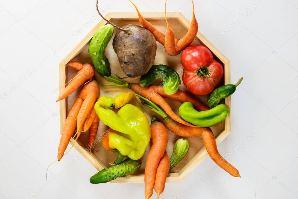 Ugly vegetables on a wooden board. Ugly food concept, top view.