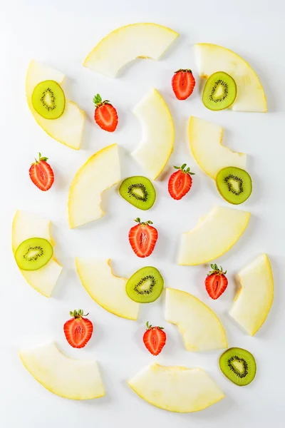 Beyaz arka planda kavun dilimleri, çilek ve kivi. Düz döşeme, dikey yönlendirme.