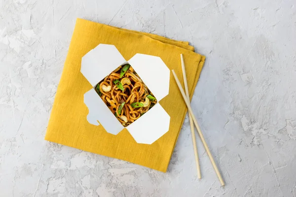 Gri bir arka plan üzerinde erişte kutusu. Asya mutfağı, yatay oryantasyon, düz yatıyordu.