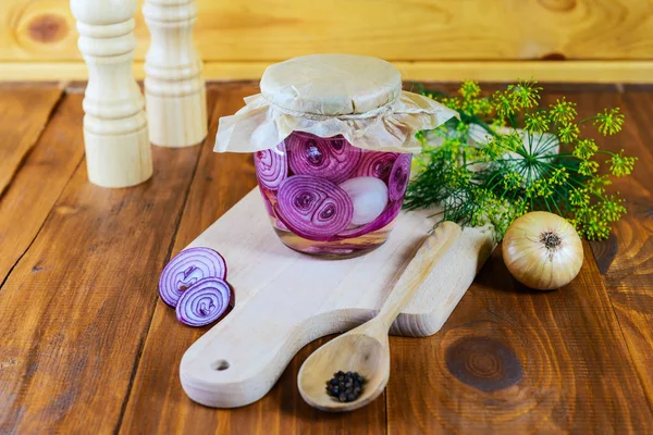 Tahta bir masanın üzerindeki kavanozda soğan turşusu. Fermente gıda.