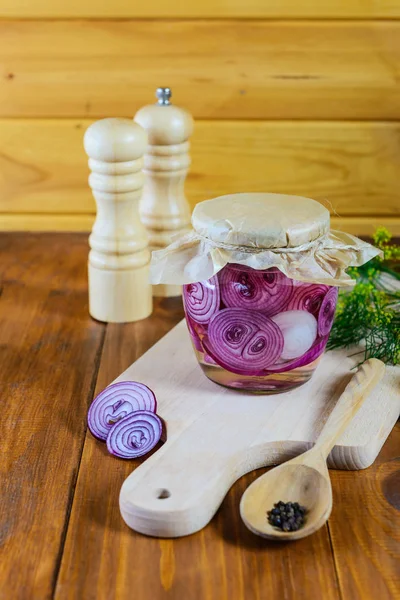 Pickled onions in a jar on a wooden board. Fermented food.