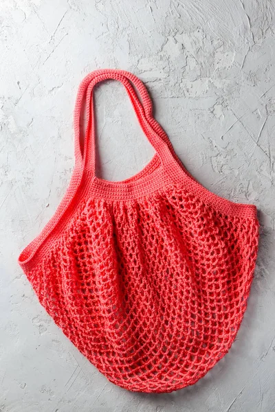 Coral string bag on a gray background. Zero waste concept, flat lay, closeup.