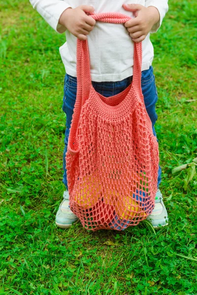 String bag with toys in the hands of a child. Zero waste concept.