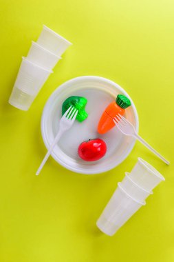 Açık yeşil arka plan üzerinde plastik bir tabak üzerinde Plastik sebzeler.