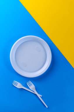 Mavi ve sarı arka planda beyaz plastik tabaklar.