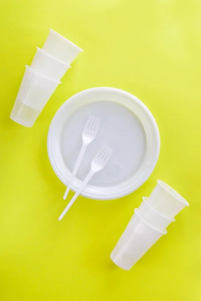 White plastic dishes on a light green background.