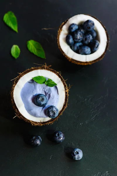 Koyu bir arka plan üzerinde bir hindistan cevizi çilek ve meyve ile Mavi matcha smoothie.