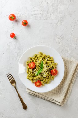 Gri bir arka plan üzerinde fesleğen, domates ve peynir ile Pesto makarna. İtalyan geleneksel mutfağı. 