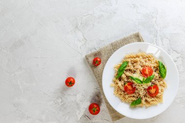 Beyaz bir tabaktabakta domates, fesleğen ve peynir ile Makarna. İtalyan geleneksel mutfağı. Düz döşeme, kopyalama alanı.