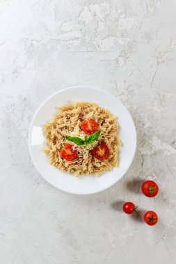 Beyaz bir tabaktabakta domates, fesleğen ve peynir ile Makarna. İtalyan geleneksel mutfağı.