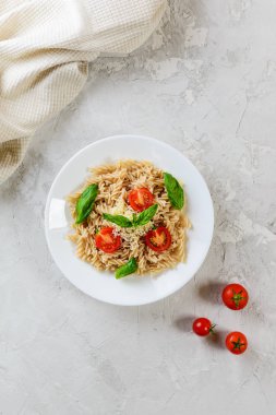 Beyaz bir tabaktabakta domates, fesleğen ve peynir ile Makarna. İtalyan geleneksel mutfağı.
