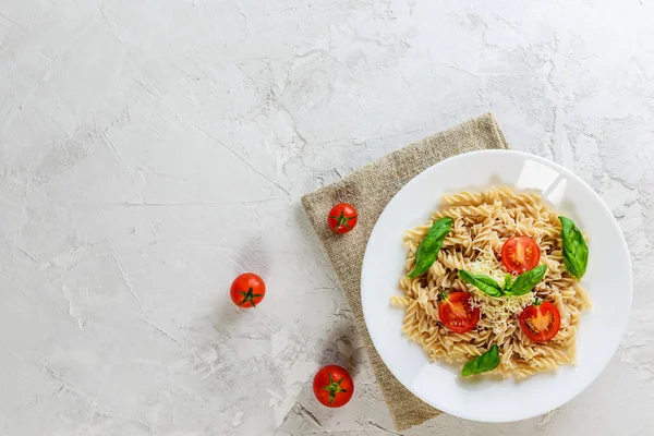 Beyaz bir tabaktabakta domates, fesleğen ve peynir ile Makarna. İtalyan geleneksel mutfağı. Düz döşeme, kopyalama alanı.