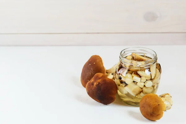 Marinated mushrooms in a jar on a light background. Fermented food, horizontal orientation, copy space.
