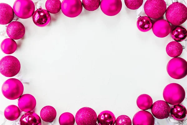 Beyaz bir arka plan üzerinde bir çerçeve şeklinde fuşya renk Noel topları.