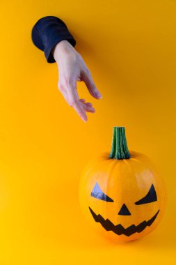 Halloween. Duvardaki bir delikten sürünen bir el ile turuncu bir arka plan üzerinde Kabak. Horisontal oryantasyon, kopyalama alanı.