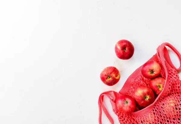 Beyaz bir arka plan üzerinde bir dize çanta kırmızı elma. Düz döşeme, kopyalama alanı.