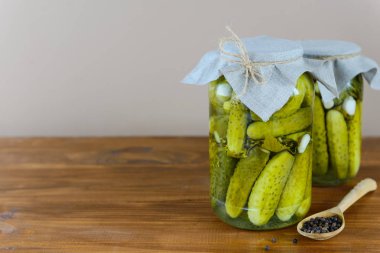 Ahşap bir masada kavanozda marine edilmiş salatalıklar. Mayalanmış yiyecek. Yatay yönelim, boşluğu kopyala.