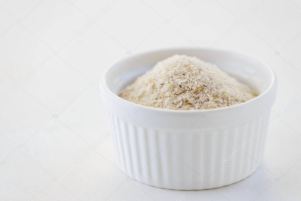 Psyllium husk in a white bowl. Natural dietary fiber for bowel regulation.