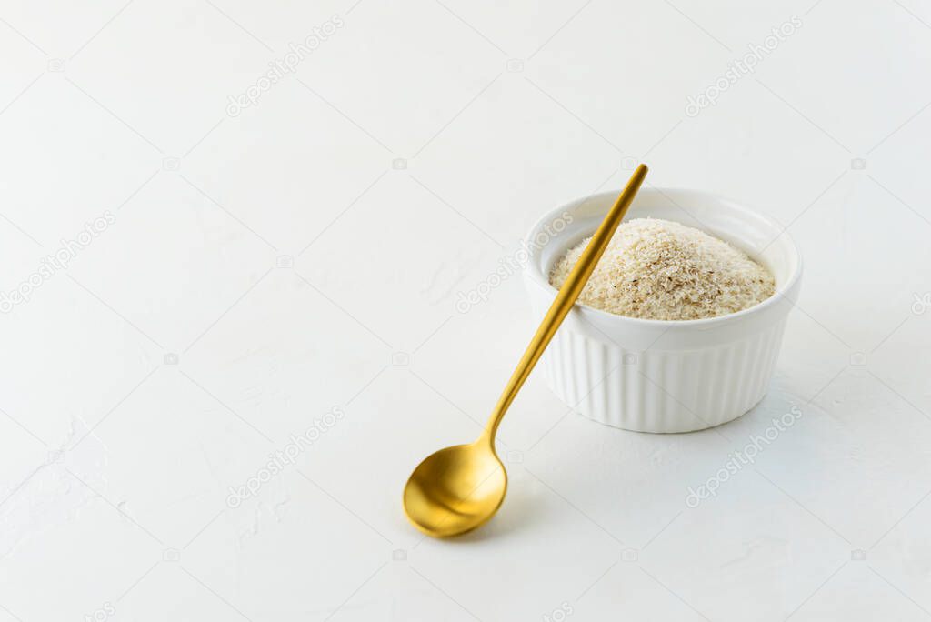 Psyllium husk in a white bowl with a spoon. Horizontal orientation, copy space.