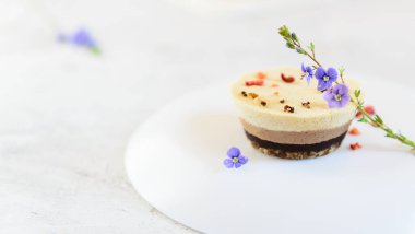 Çiçeklerle süslenmiş kaju fıstığı keki ve süblimleşmiş böğürtlenler. Yatay yönelim, boşluğu kopyala.