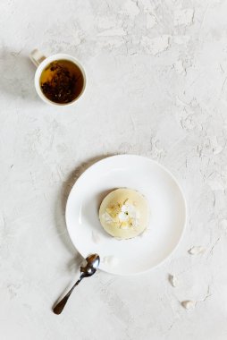 Beyaz tabakta çiğ bademli kek ve bir fincan çay. Dikey yönelim, üst görünüm.