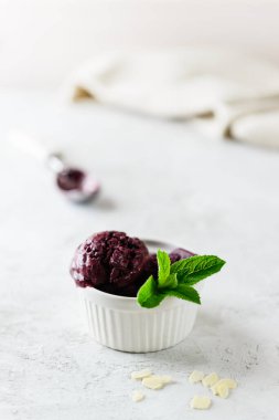 Gri bir masada nane yapraklı yaban mersinli dondurma. Şeker ve laktozsuz.
