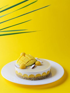 Mangolu kaju keki ve sarı arka planda hindistan cevizi ve yeşil yapraklar. Şeker, laktoz, glütensiz. Sağlıklı yemek, vejetaryen..