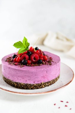 Çikolatalı granola üzerine ev yapımı çiğ kaju üzümlü siyah frenk üzümü keki. Tabakta taze böğürtlenlerle süslenmiş. Şeker, laktoz, glütensiz.