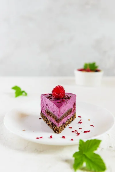 A piece of mousse cashew cake made from blackcurrant and chocolate praline. Sugar, lactose, gluten free. Vegan dessert, healthy food.