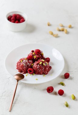 Aquafaba 'dan ev yapımı ahududu dondurması ve beyaz tabakta şam fıstığı. Şeker, laktoz, glütensiz.