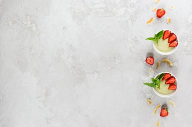 Çilekli avokado panna cotta ve beyaz kaselerde nane şekeri. Şeker, laktoz, glütensiz. Sağlıklı yemek, diyet, vejetaryen. Yatay yönelim, kopyalama alanı, üst görünüm.