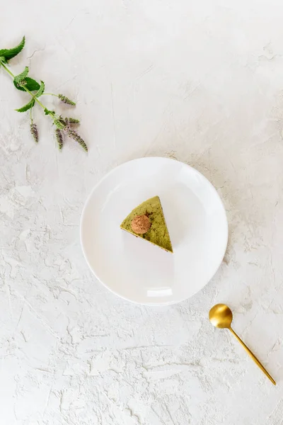 A slice of chocolate mint cashew cake with matcha on a white plate. No sugar, lactose, gluten. Vertical orientation, top view.