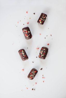 Fıstıklı ve çilekli çikolatalar beyaz bir masada. Şeker, laktoz, glütensiz. Sağlıklı yemek, vejetaryen. Dikey yönelim, üst görünüm.