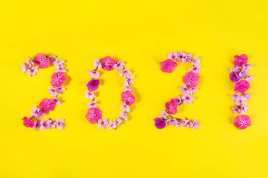Yeni Yıl 2021 Sarı arka planda pembe çiçeklerden yapılmıştır.