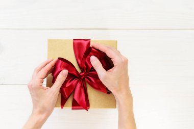 Eller hediye kutusunda fiyonk tutuyor. Yatay yönelim, üst görünüm, kopyalama alanı.