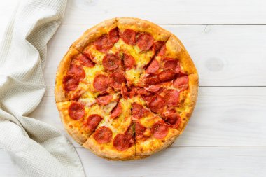 Açık ahşap bir masada peperonili pizza. Yatay yönelim, üst görünüm, düz yatış.