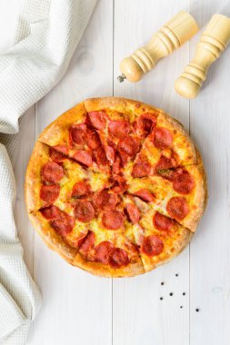 Açık ahşap bir masada peperonili pizza. Dikey yönelim üst görünümü, düz yatay.
