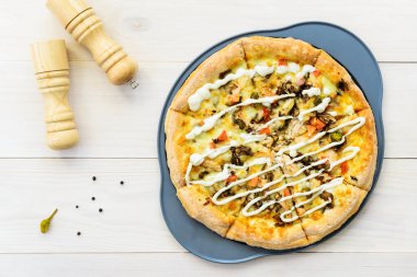 Tavuklu, domatesli, biberli, peynirli ve soslu pizza. Yatay yönelim, üst görünüm, düz yatış.